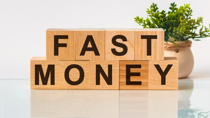 FAST MONEY motivation text on wooden blocks business concept white background. Front view concepts, flower in the background.