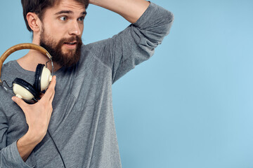 Man with headphones in hands music emotion technology lifestyle fun blue background close-up