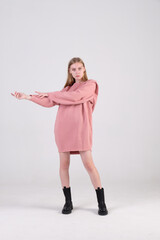 Ukrainian young fashion model wearing   pink oversized dress and black boots posing in studio cyclorama.