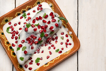 Mexican stuffed poblano peppers also called nogada with pomegranate on white background