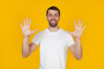Modern young man with a beard in a white tank top shows number nine with fingers on hand smiling...