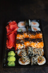 fresh sushi rolls salmon fish flying fish roe vegetables ginger wasabi rice and nori on the table serving size top view place copy space for text food background rustic