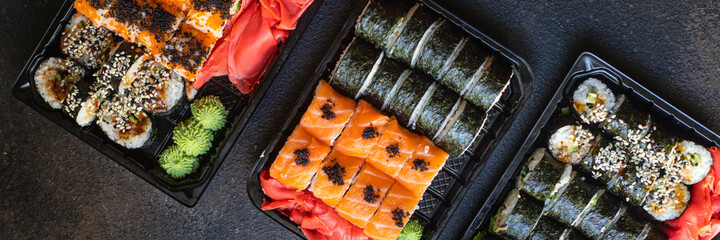 fresh sushi rolls salmon fish flying fish roe vegetables ginger wasabi rice and nori on the table...