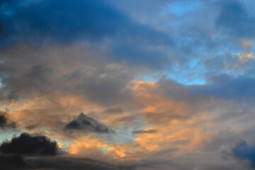 tufts of clouds shaded with gray and orange covering a twilight blue sky.