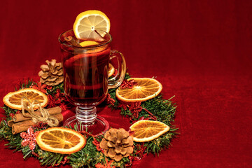 inter drink. Cherry mulled wine in a beautiful mug in the middle of a Christmas wreath on a red background.