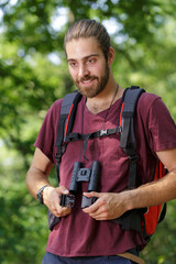 young male hiker with binoculars in forest
