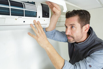 focused handyman testing air conditioning on the wall