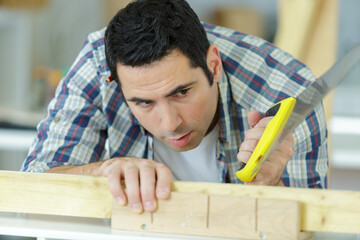 man sawing cutting wood board