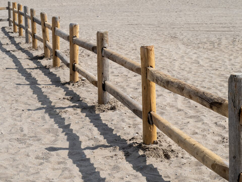 a wooden log rail and post fence like a corral on a beach sand dune