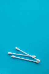 Cotton ear swabs sticks on blue background. close up. Image with selective focus, noise effect and toning. Top view. Flat lay.
