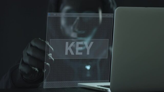 Hacker wearing black mask pulls KEY tab from a laptop