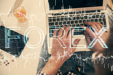 Double exposure of man's hands typing over laptop keyboard and forex chart hologram drawing. Top view. Financial markets concept.
