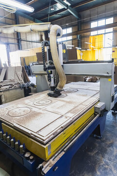 large cnc machine cuts blanks of various shapes on a plywood sheet