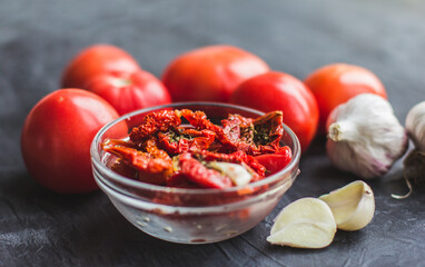 Dried tomatoes with garlic and olive oil in a bowl on a gray table background