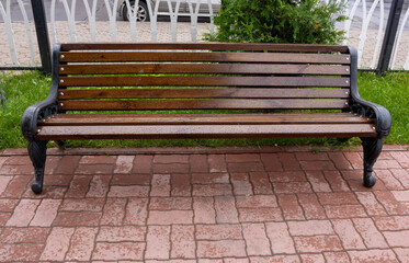 A rain-soaked brown bench in an autumn Park