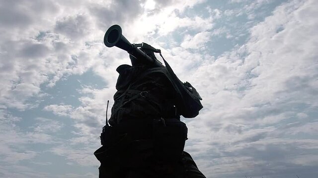A soldier in camouflage fires active-reactive grenades from a reusable hand-held anti-tank grenade launcher in a sitting position