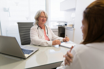 Serious older female doctor with pen listening to patient at medical clinic healthcare, clinic,...
