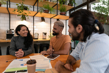 Group of latin business colleagues planning business future, checking reports in office or...