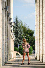 A blonde girl in a leopard dress poses candidly in a deserted city. Empty streets