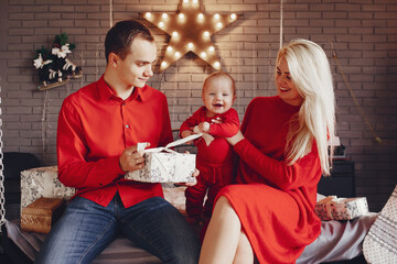 Beautiful mother in a red dress. Family sitting on a bed. Little child with parents