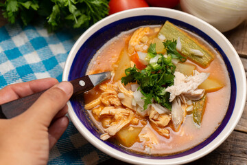 Mexican chicken soup with vegetables and rice on wooden background