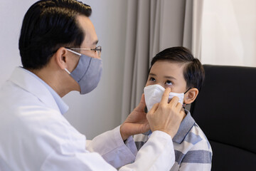 Portrait ophthalmologist examining the eyes of an Asian man in a clinic. They wear protective face masks.