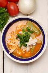 Mexican chicken soup with vegetables and rice on white background
