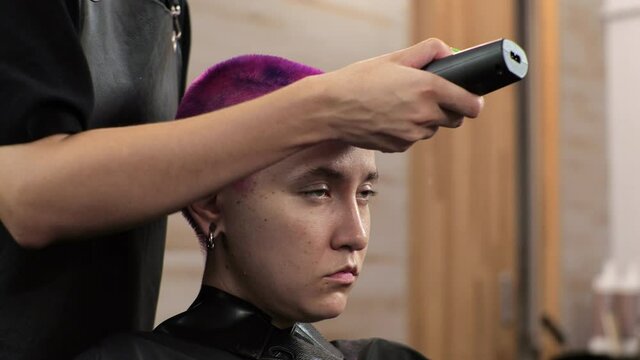Hairdresser cuts short hair with a clipper. Home salon during the epidemic.