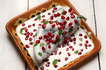 Mexican stuffed poblano peppers also called nogada with pomegranate on white background