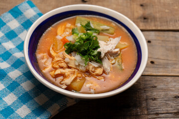Mexican chicken soup with vegetables and rice on wooden background