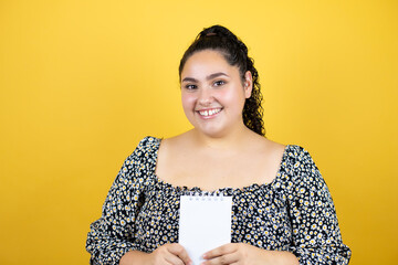 Young beautiful woman with curly hair over isolated yellow background