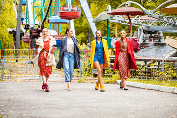 Four fashion models walking in autumn park