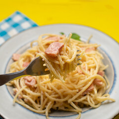 creamy spaghetti pasta with ham on yellow background