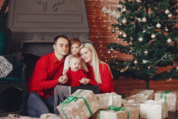 Beautiful mother in a red dress. Family sitting near christmas gifts. Little girl and boy near christmas tree