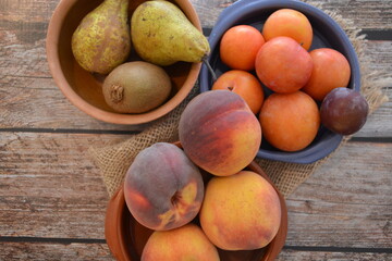 Fototapeta na wymiar frutta fresca sul tavolo pesche pere kiwi