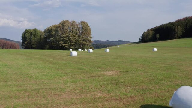 wrapped hay bales from above on a large agricultural meadow filmed in 4k