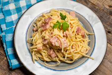 creamy spaghetti pasta with ham on wooden background