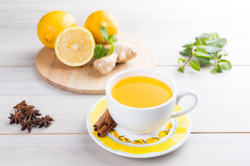 Cup of lemon tea with ginger. On a white wooden table