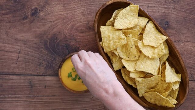 Dipping a Tortilla Chip into Queso Cheese Sauce