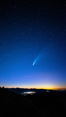 Vertical shot of a shooting star in the gorgeous sky over a city at dusk © Daniel Rot/Wirestock