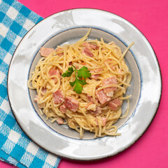 creamy spaghetti pasta with ham on pink background