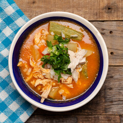 Mexican chicken soup with vegetables and rice on wooden background