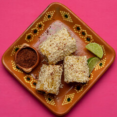 Fototapeta na wymiar Mexican corn on the cob also called elotes with cheese and mayonnaise on pink background