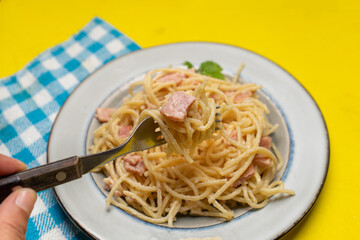 creamy spaghetti pasta with ham on yellow background