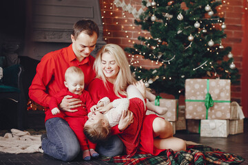 Beautiful mother in a red dress. Family sitting near christmas gifts. Little girl and boy near christmas tree