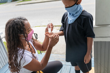 African American Mother Using Hand Sanitizer with young seven year old son