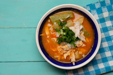 Mexican chicken soup with vegetables and rice on turquoise background