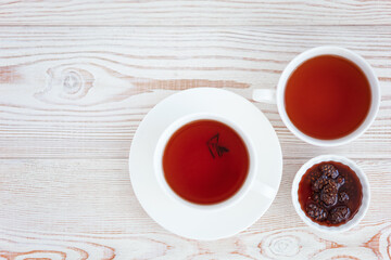 tea and jam of cones on a light wooden background top view.
