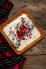 Mexican stuffed poblano peppers also called nogada with pomegranate on wooden background