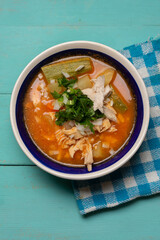 Mexican chicken soup with vegetables and rice on turquoise background